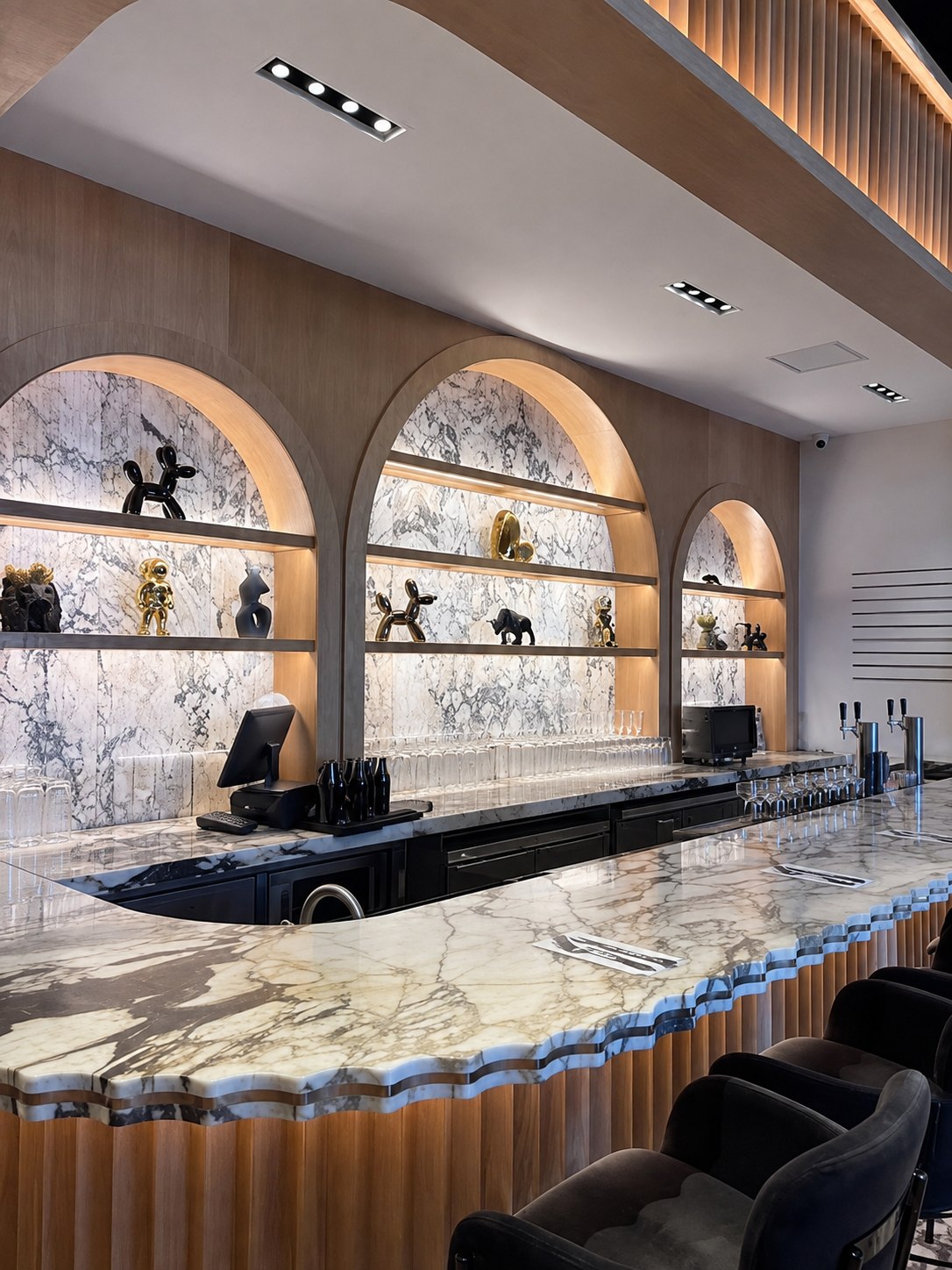 The curved marble coffee bar at Crave Café, backed by three lit arches of marble shelving